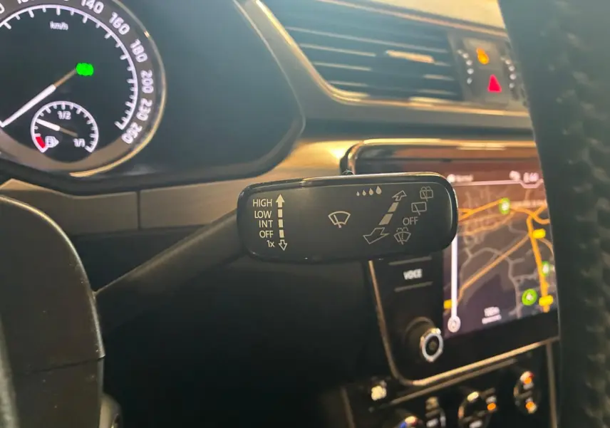 Gros plan sur la commande d’essuie-glace côté droit du tableau de bord d’une Skoda Superb Combi bleu, avec écran GPS en arrière-plan.