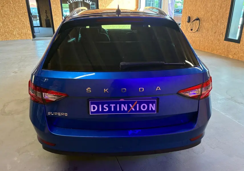 Vue arrière d'un Skoda Superb Combi bleu 2021 avec feux arrière allongés et plaque d'immatriculation Distinxion.