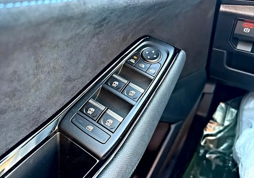 Gros plan sur la commande des vitres électriques côté conducteur du Renault Austral noir, avec revêtement noir et alcantara.