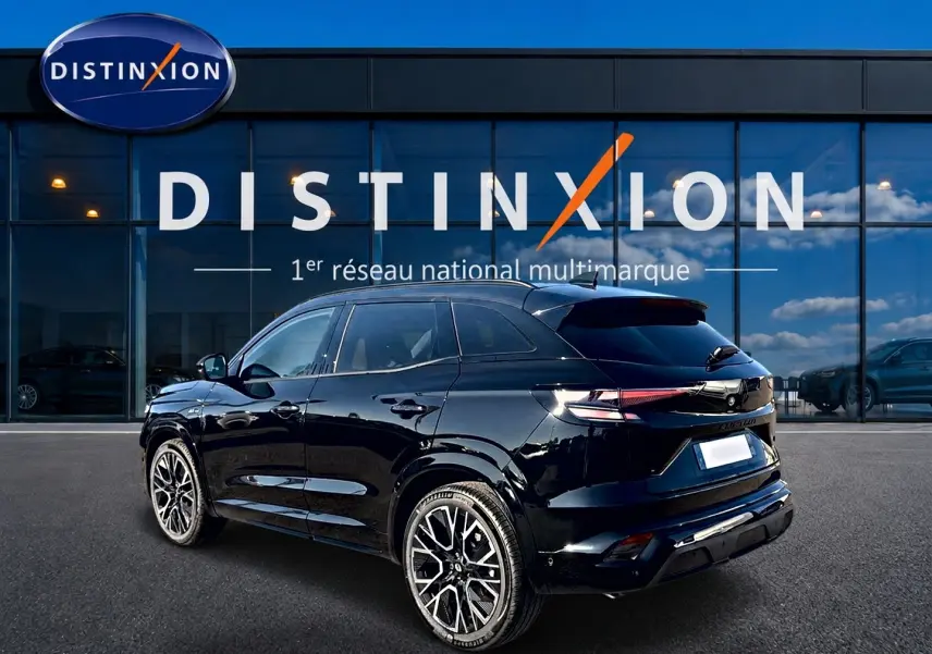 Renault Austral noir en 3/4 arrière droit, jantes alu distinctives, stationné devant une vitrine Distinxion.