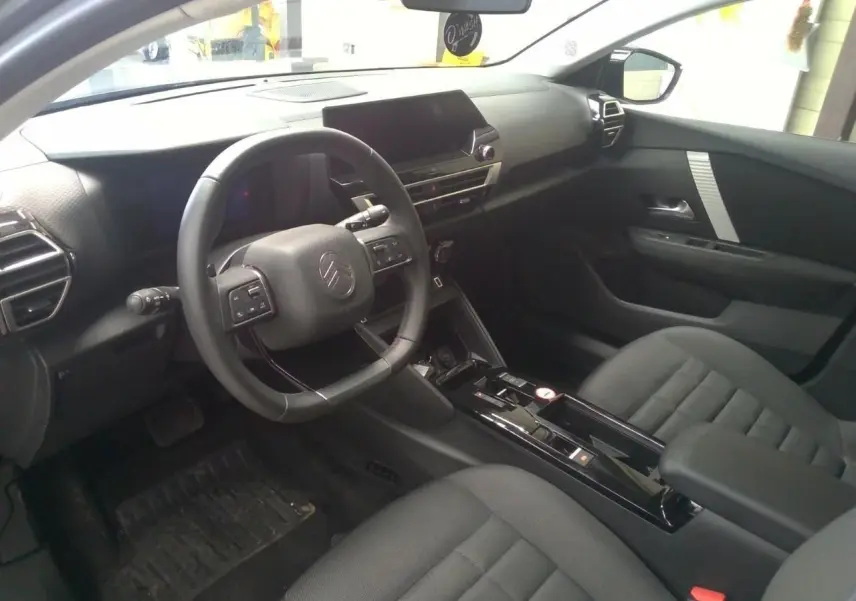 Intérieur avant droit de la Citroën C4 hybride 2025, tableau de bord moderne avec écran tactile et volant multifonction noir.