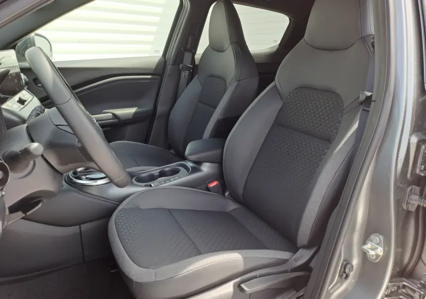 Vue intérieure côté conducteur du Nissan Juke Hybrid 143 N-Connecta 2025 en gris squale, sièges noirs tissu et cuir.
