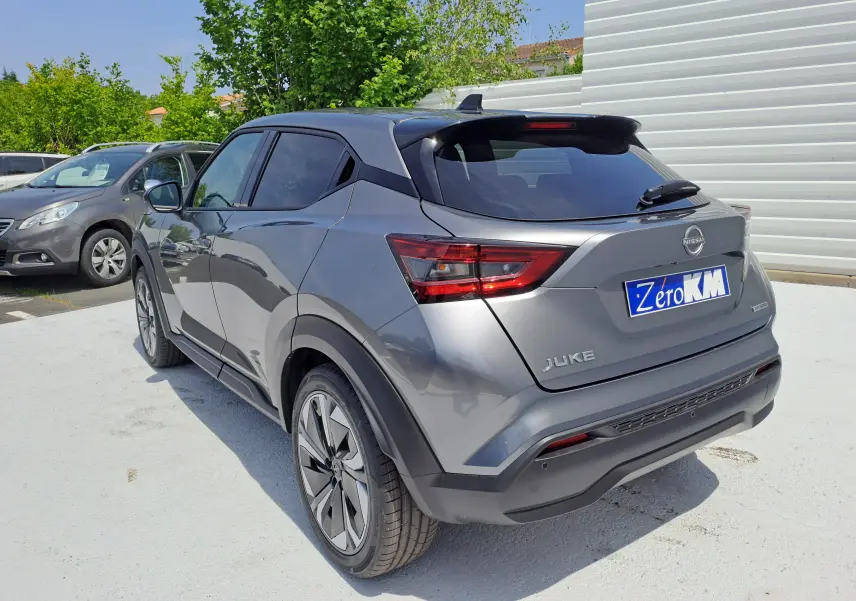 Vue 3/4 arrière droite d'un Nissan Juke Hybrid 143 N-Connecta gris squale avec vitres teintées et jantes alliage.