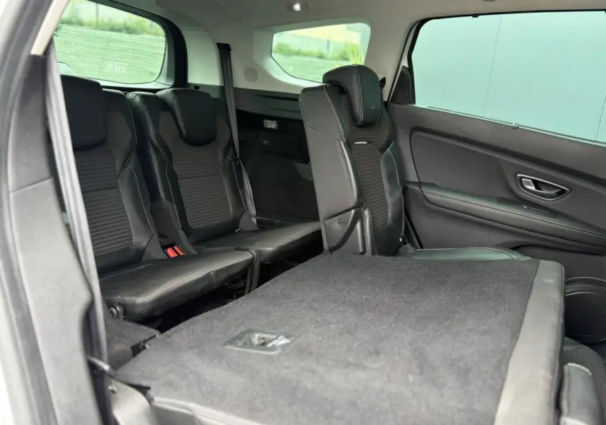 Vue intérieure côté droit du Renault Grand Scenic IV montrant les sièges arrière noirs et une banquette rabattue.