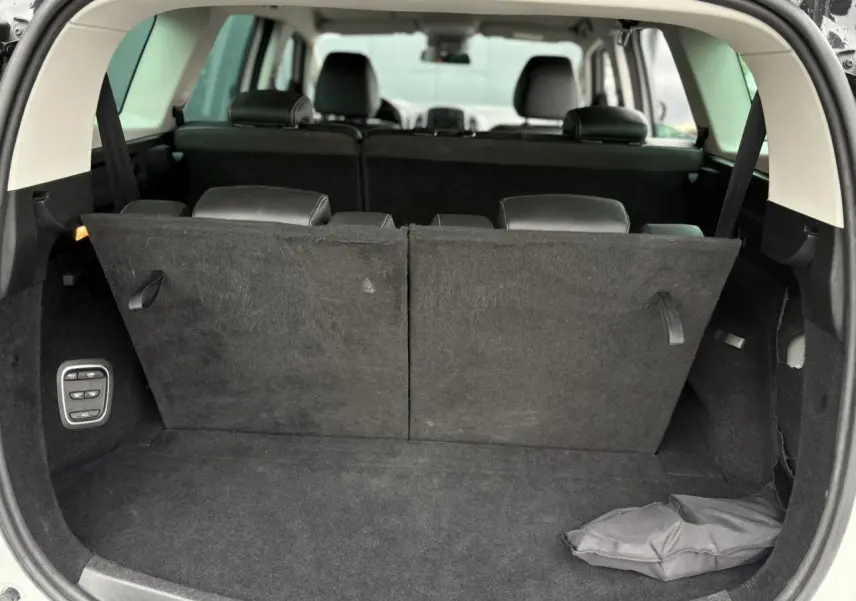 Coffre ouvert d'un Renault Grand Scenic blanc nacré, montrant la troisième rangée de sièges rabattue partiellement.