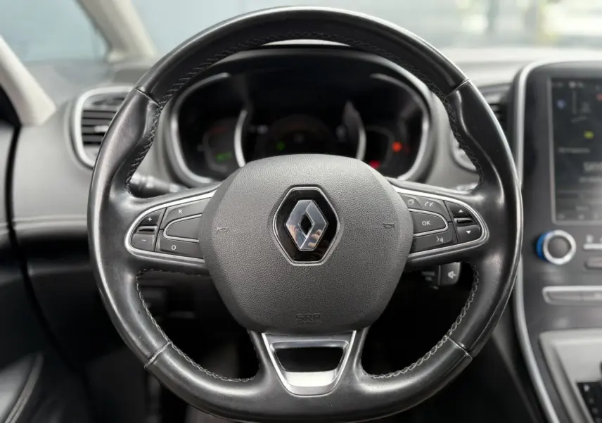 Volant en cuir noir avec logo Renault au centre, tableau de bord et écran tactile du Renault Grand Scenic IV visibles en arrière-plan.