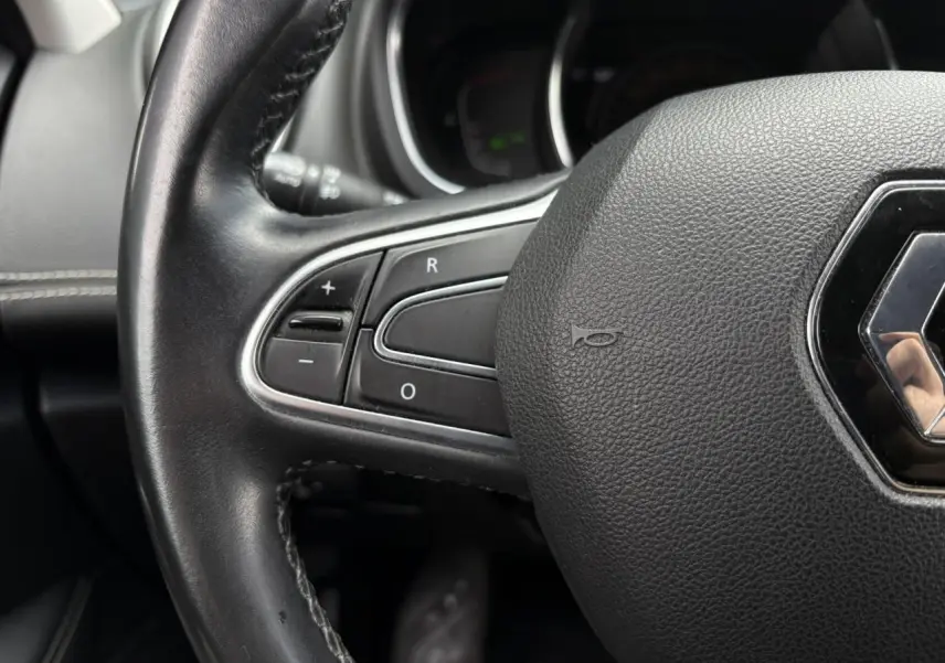Gros plan sur le volant cuir noir du Renault Grand Scenic IV avec commandes intégrées sur le côté gauche.