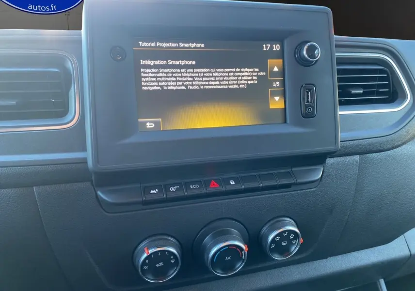 Écran tactile central avec tutoriel smartphone et commandes de climatisation dans l'habitacle noir du Renault Master blanc 2023