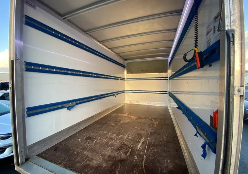 Intérieur du coffre blanc du Renault Master Châssis Cabine 2023 vu de l'arrière, avec rails de fixation bleus et plancher usé.