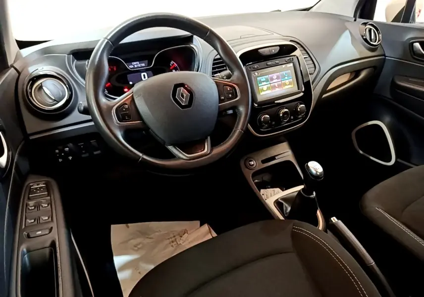 Vue intérieure côté conducteur du tableau de bord noir du Renault Captur avec volant cuir et écran tactile central.