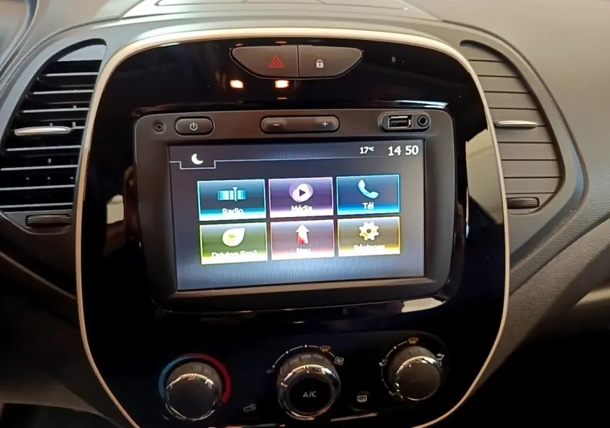 Vue rapprochée du tableau de bord noir du Renault Captur Business 2018 avec écran tactile central allumé et commandes de climatisation.