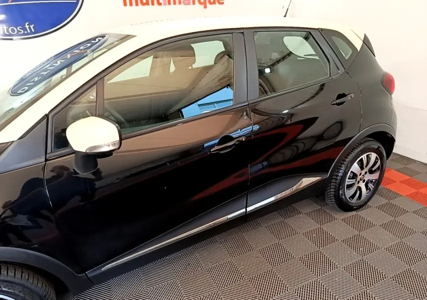 Profil côté gauche du Renault Captur noir avec rétroviseur blanc et jantes alliage visibles en intérieur showroom.