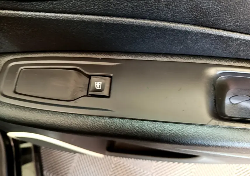 Gros plan sur le bouton de commande de la vitre électrique côté conducteur du Renault Captur Business noir de 2018.