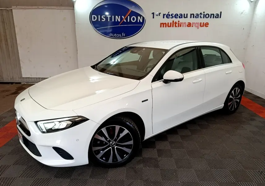 Vue 3/4 avant droite d'une Mercedes Classe A Berline blanche avec jantes noires et phares LED allumés.