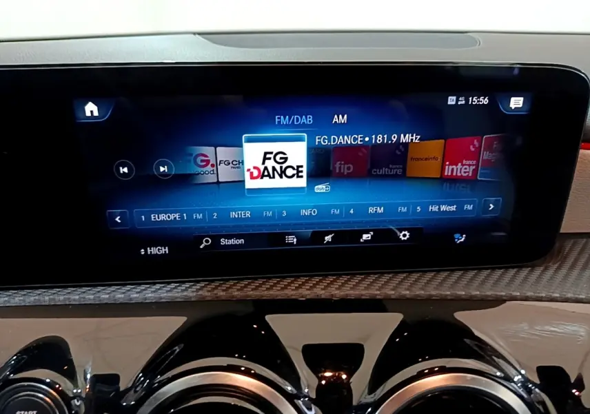 Écran tactile central affichant la radio FM/DAB dans l’habitacle d’une Mercedes Classe A blanche, vue de face rapprochée.