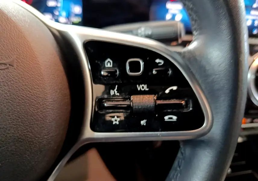 Gros plan sur le volant cuir multifonctions côté gauche de la Mercedes Classe A Berline blanche de 2020.