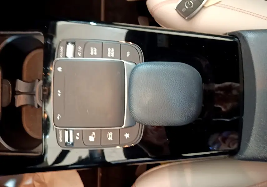 Vue plongeante sur la console centrale noire brillante de la Mercedes Classe A 250 e Business Line avec pavé tactile et pommeau cuir.