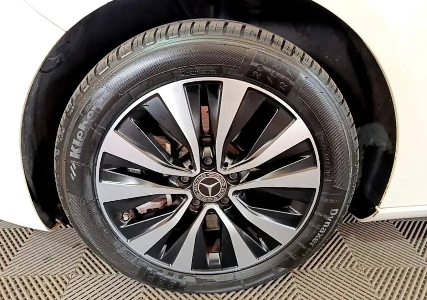 Gros plan sur la roue avant droite d’une Mercedes Classe A blanche avec jante alliage bicolore et logo central.