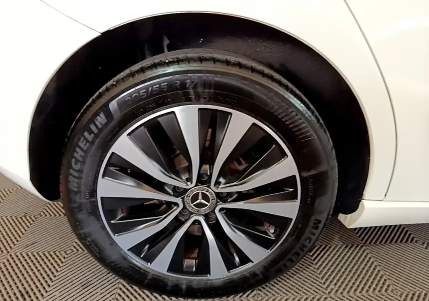 Gros plan sur la roue arrière droite d'une Mercedes Classe A blanche, jante alliage noir et argent avec pneu Michelin.