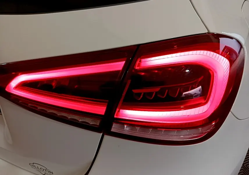 Gros plan sur le feu arrière droit rouge vif d’une Mercedes Classe A Berline blanche, version hybride rechargeable.