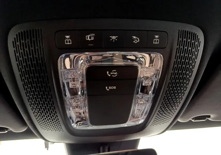 Gros plan sur la console de toit noire avec commandes d’éclairage et boutons SOS d’une Mercedes Classe A blanche.