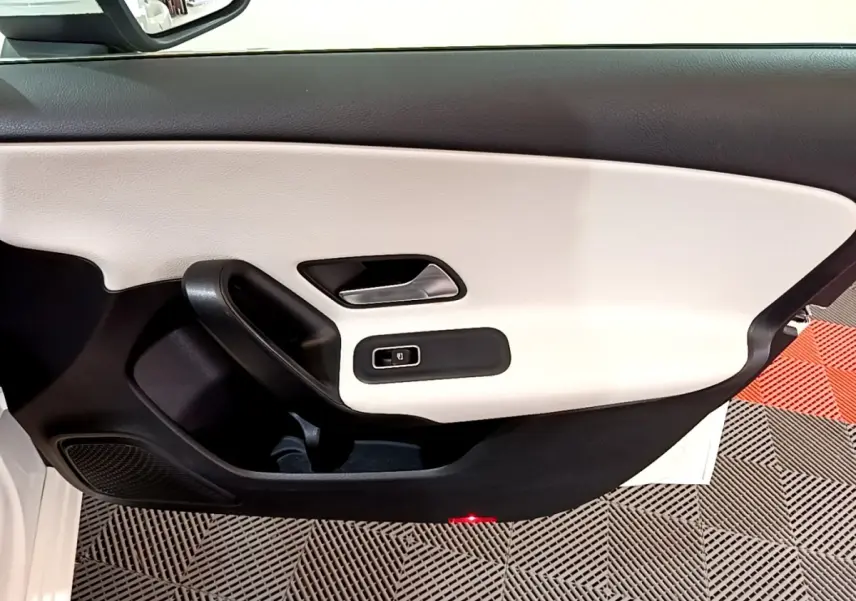Vue rapprochée de la porte avant gauche blanche de la Mercedes Classe A Berline avec garniture bicolore noir et beige.