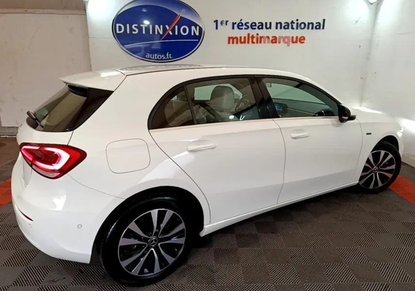 Vue côté droit arrière d'une Mercedes Classe A Berline blanche avec feux arrière LED allumés dans un showroom.