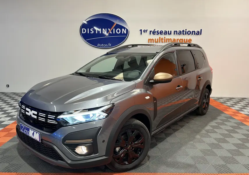 Dacia Jogger gris schiste métal en 3/4 avant droit, avec jantes noires et rétroviseurs couleur or mat.