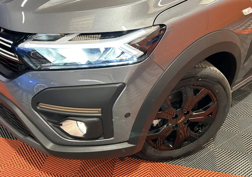 Gros plan sur l'avant droit gris schiste métallisé du Dacia Jogger avec phare LED et jante noire au design distinctif.