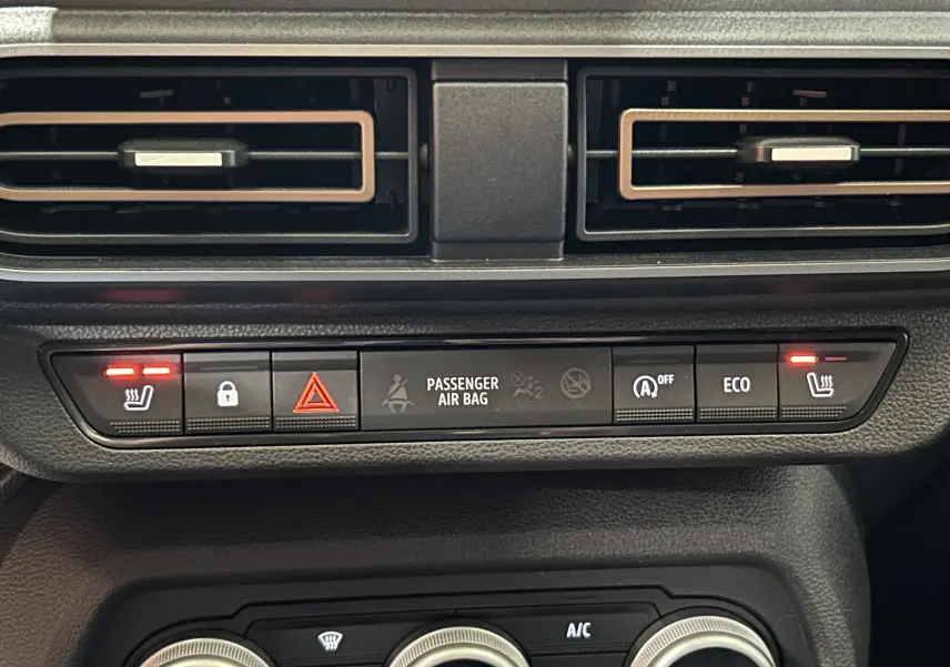 Gros plan sur la console centrale du Dacia Jogger gris, montrant les commandes de sièges chauffants et boutons de sécurité.