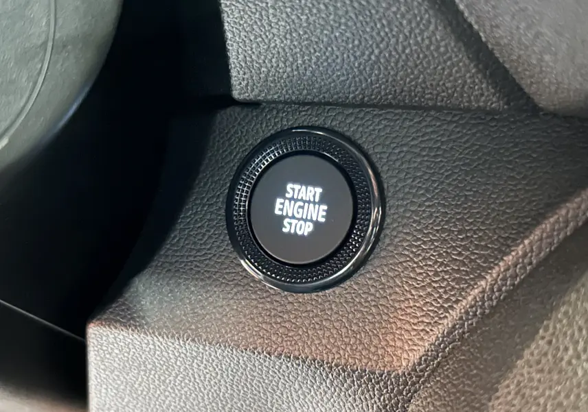 Bouton Start Engine Stop en gros plan sur tableau de bord noir texturé du Dacia Jogger 2026.