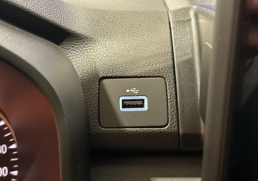 Gros plan sur la prise USB encadrée de bleu sur le tableau de bord noir du Dacia Jogger Gris Schiste Métal.