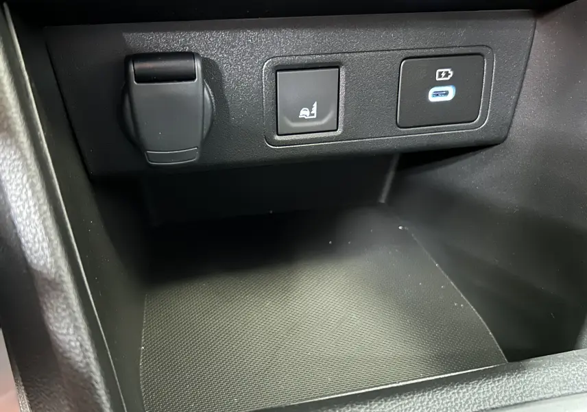 Détail intérieur du compartiment central avec prise 12V, bouton de fonction et port USB-C éclairé sur Dacia Jogger 2026.