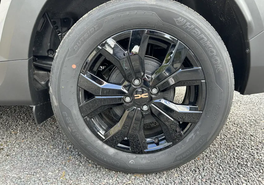 Gros plan sur la jante noire brillante de la roue avant droite du Dacia Jogger gris schiste métal.
