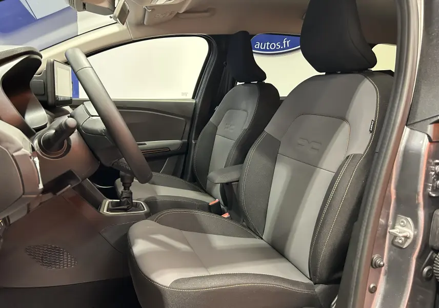 Vue intérieure côté conducteur du Dacia Jogger gris schiste, sièges tissu noir avec surpiqûres jaunes et volant multifonction.