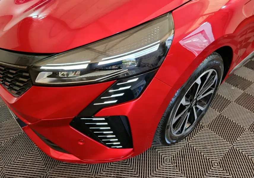 Gros plan sur l'avant droit rouge vif de la Renault Clio 2024 Techno TCe 90 avec ses phares LED distinctifs et jante alliage.