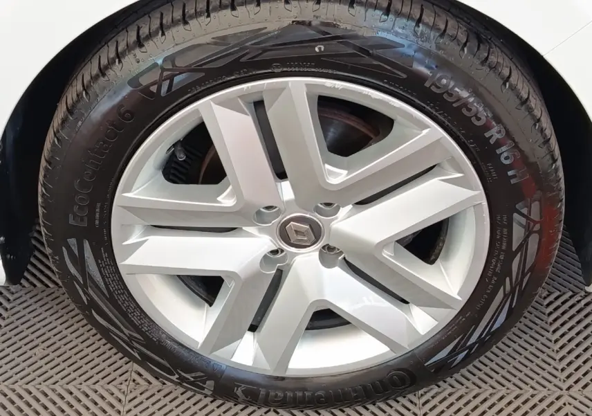 Gros plan sur la roue avant droite d'une Renault Clio blanche avec jante alliage et logo Renault central.