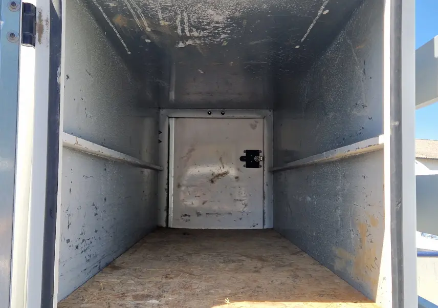 Vue rapprochée du mécanisme de benne relevée d’un Renault Master blanc, montrant le vérin hydraulique et le châssis métallique.