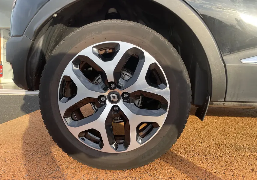 Gros plan sur la roue avant droite du Renault Captur noir étoile avec jante alliage bicolore 17 pouces.