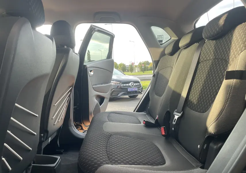 Vue intérieure arrière droite du Renault Captur noir étoile avec sièges tissu gris beige et porte arrière ouverte.