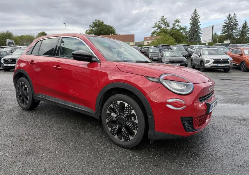 Fiat 600 rouge vue 3/4 avant droit, avec jantes alliage noires et toit noir brillant sur parking humide.