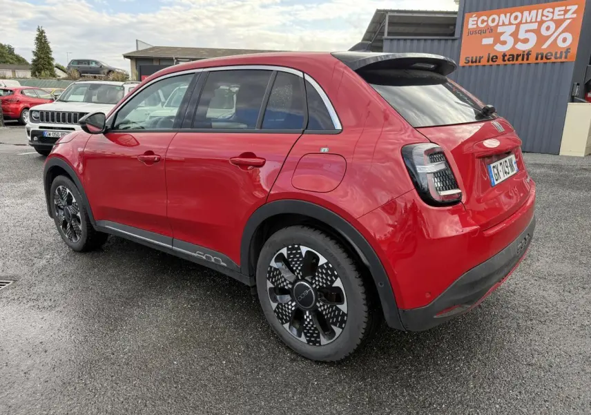 Vue 3/4 arrière droite d'une FIAT 600 La Prima rouge avec jantes alliage 18'' diamantées et antenne requin noir brillant.