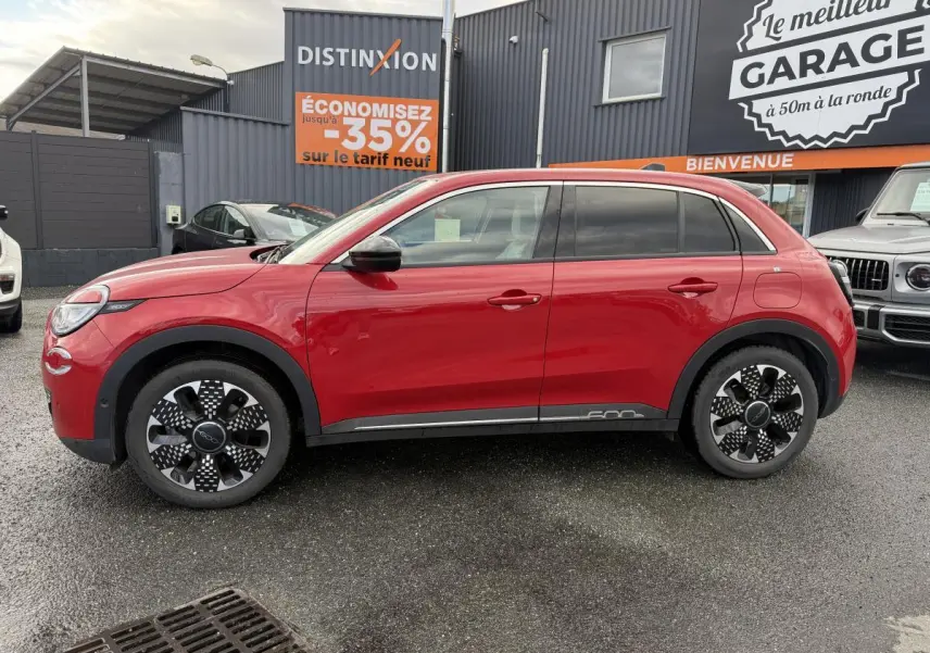 Profil côté gauche d'une FIAT 600 1.2 Hybrid rouge avec jantes alliage 18'' diamantées et vitres surteintées.