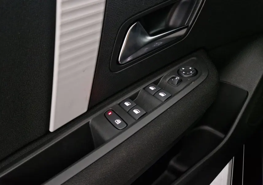 Gros plan sur la commande des vitres et rétroviseurs côté conducteur de la porte noire d'une Citroën C4 2025.
