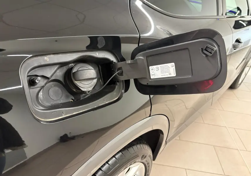 Gros plan sur la trappe à carburant ouverte côté gauche d’un CUPRA Formentor noir minuit, avec bouchon essence visible.