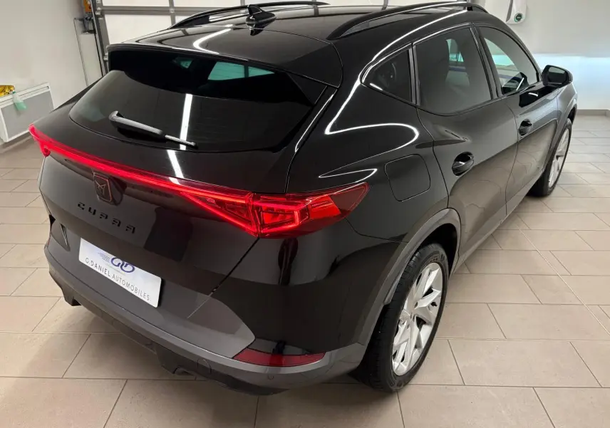 Vue 3/4 arrière droite du CUPRA Formentor 1.5 TSI 150 DSG7 noir minuit avec feux arrière continus et toit panoramique.