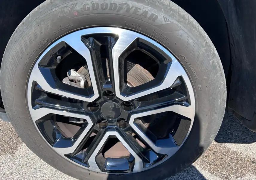 Gros plan sur la jante alliage 18 pouces bicolore noir et argent du Jeep Compass gris 2024.