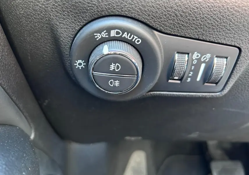 Gros plan sur le bouton de commande des phares et réglages d’éclairage du Jeep Compass gris 2024, intérieur noir.
