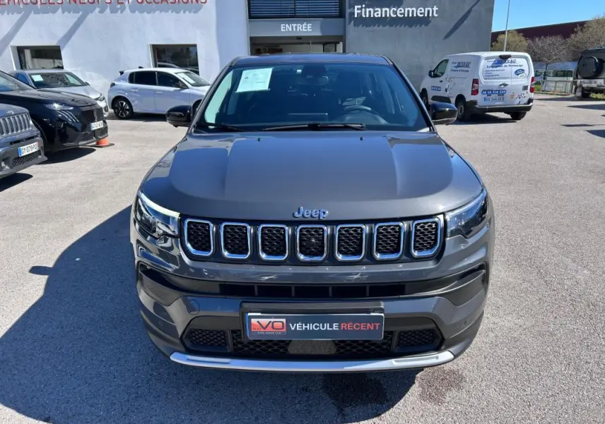 Vue avant d'un Jeep Compass gris 2024 avec calandre à sept ouvertures et plaque "Véhicule récent" visible.