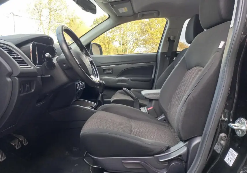 Vue intérieure côté conducteur du Mitsubishi ASX noir 2020, mettant en valeur les sièges et l'accoudoir central.